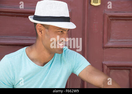 Ritratto di un ambiguo etnicamente uomo che indossa una fedora e luce maglia verde all'esterno. Foto Stock