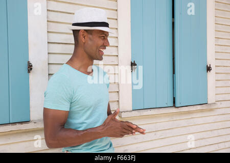 Ritratto di un ambiguo etnicamente uomo che indossa una fedora e luce maglia verde all'esterno. Foto Stock