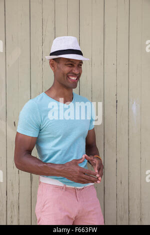 Ritratto di un ambiguo etnicamente uomo che indossa una fedora e luce maglia verde all'esterno. Foto Stock