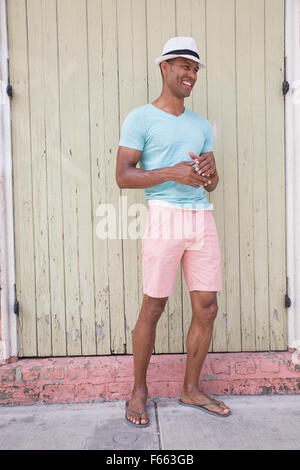 Ritratto di un ambiguo etnicamente uomo che indossa una fedora e leggera camicia verde esterno. casual estate fotografia di stock Foto Stock