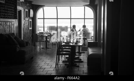 Un uomo e una donna seduti a un tavolo in un ristorante con una finestra dietro di loro. Foto Stock