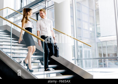 Colleghi di lavoro parlando su scale e flirtare Foto Stock