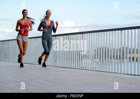 Due donne sportivi jogging in città mentre si ascolta la musica Foto Stock