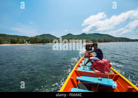 Uomo locale lo sterzo longtail boat dalla parte posteriore, il mare turchese, isola di Koh Tao, Golfo di Thailandia, Tailandia Foto Stock