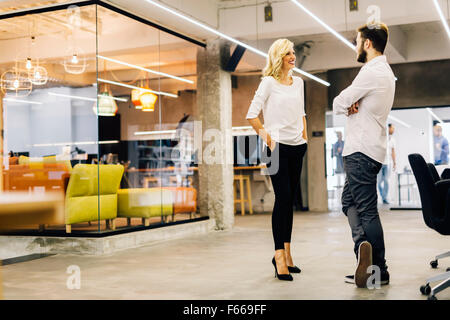 Due colleghi intelligenti che parlano in un ufficio moderno Foto Stock