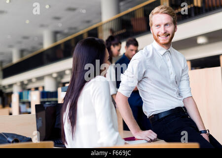 Un gruppo di docenti universitari che studiano nella libreria e conversare in uno stato d'animo positivo Foto Stock