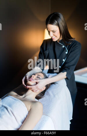 Massaggiatore trattare la faccia di una bella e giovane donna disteso sul lettino da massaggio Foto Stock