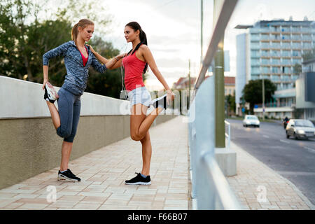 Due donne stretching piedi prima di fare jogging Foto Stock