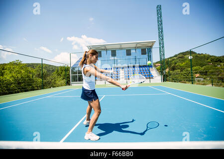 Femmina giocatore di tennis di eseguire un drop shot su una bella corte blu Foto Stock