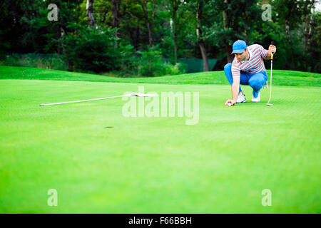 Giocatore di Golf palla di marcatura sul putting green prima del sollevamento della sfera Foto Stock