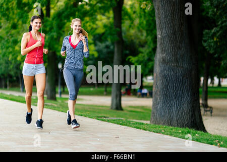 Due donne a fare jogging nel parco e ascolto di musica Foto Stock