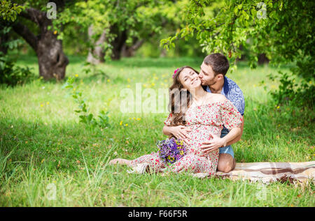 Felice coppia giovane aspetta baby sitter su erba verde Foto Stock