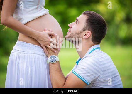 Giovane uomo guardando la sua moglie incinta e toccando il suo ventre Foto Stock