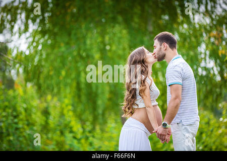 Felice coppia giovane aspetta baby in estate park Foto Stock