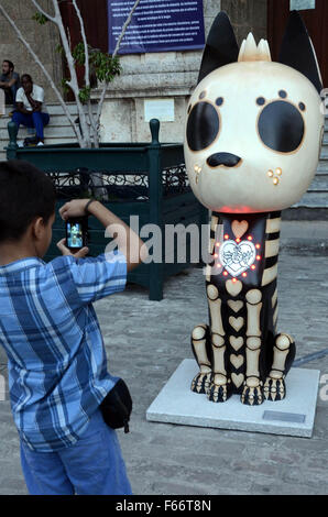 L'Avana, Cuba. Xii Nov, 2015. Un ragazzo prende le immagini di una scultura durante una mostra intitolata "Xico's viaggi in America Latina " in San Francisco Square di l'Avana, nov. 12, 2015. Sedici sculture di Xico, un cartoon xoloitzcuintle creato dall'artista messicano Cristina Pineda, sono stati esposti nella mostra. © Joaquin Hernandez/Xinhua/Alamy Live News Foto Stock