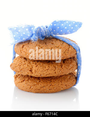 Pila di tre in casa i fiocchi d'avena cookie legate con nastro blu in piccoli e bianchi pois, isolati su sfondo bianco Foto Stock
