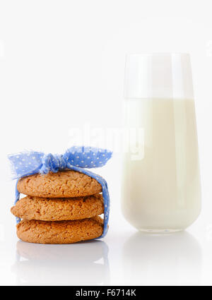 Pila di tre in casa i fiocchi d'avena cookie legate con nastro blu in piccoli e bianchi a pois e bicchiere di latte Foto Stock