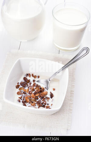 Muesli con latte in un recipiente su tavolo bianco Foto Stock