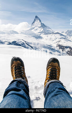 Gli uomini per le gambe in scarpe da trekking giacente sulla neve con lo  sfondo del Cervino, Svizzera Foto stock - Alamy