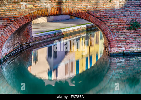 I colori intensi delle abitazioni storiche di Comacchio, città conosciuta come la piccola Venezia in Emilia Romagna, un incantevole città lagunare con ponti e canali in esecuzione attraverso di esso Foto Stock