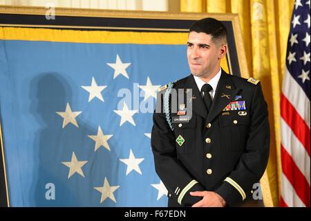 Washington, DC, Stati Uniti d'America. Xii Nov, 2015. Ritirato U.S. Esercito Capt. Florent Groberg ascolta il Presidente Barack Obama durante la medaglia d'onore alla cerimonia di premiazione nella Sala Est della Casa Bianca Novembre 12, 2015 a Washington, DC. Groberg ha ricevuto la medaglia per le azioni durante il servizio in Afghanistan quando ha affrontato un attentatore suicida, salvando le vite di molti ma di essere gravemente feriti nel processo. Foto Stock