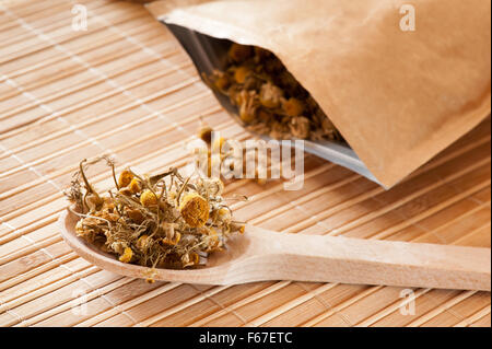 Il cucchiaio di legno con secchi i fiori di camomilla, un bouquet di fiori  freschi di camomilla fiori su uno sfondo di tavole di legno Foto stock -  Alamy