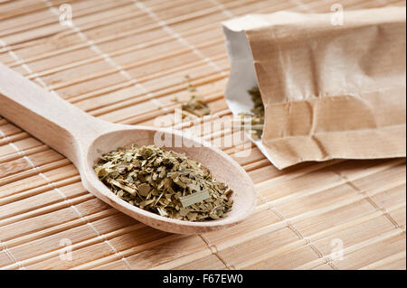 Essiccato yerba mate con Citronella lascia parte del tè giacente sul cucchiaio di legno sul tappetino, pila di verde tè Mate noto come Chimarrao... Foto Stock