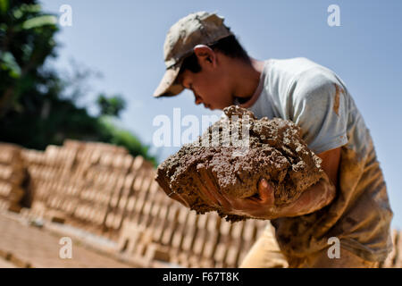 Moisés, un tredici-anno-vecchio ragazzo di El Salvador, trasporta argilla cruda per mattone facendo ad una fabbrica di mattoni in Istahua, El Salvador. Foto Stock