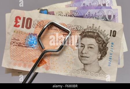 British 10 e 20 pound note essendo mantenuto in pinze in metallo Foto Stock