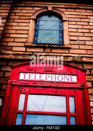 Basso angolo di visualizzazione di un vecchio telefono chiosco al di fuori della santa Chiesa della Trinità nel centro citta' di Warrington Foto Stock