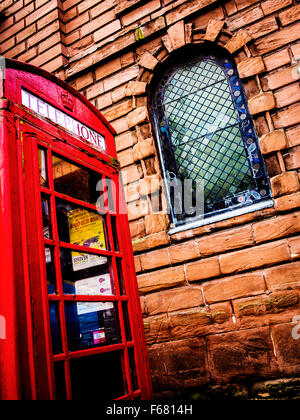 Basso angolo di visualizzazione di un vecchio telefono chiosco al di fuori della santa Chiesa della Trinità nel centro citta' di Warrington Foto Stock