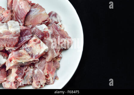 Cumulo di carne di maiale cruda ossa su piastra bianca Foto Stock