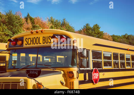 Giallo scuola bus nel parcheggio contro autunno alberi con bel cielo azzurro Foto Stock