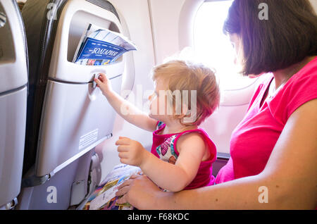 Madre di viaggiare con un anno di età bambino su un aereo Foto Stock