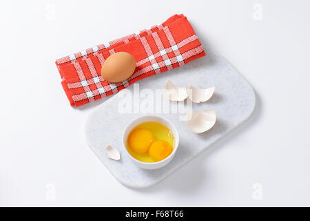 Freschi gli albumi e tuorli nella ciotola bianco Foto Stock