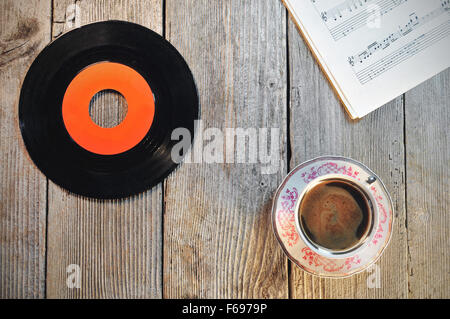 Vecchi dischi in vinile, una tazza di caffè e note musicali su un tavolo di legno Foto Stock