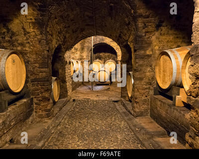 Più in legno barili di vino stoccato in un antica cantina medievale si trova a Neive, città nelle Langhe. Foto Stock