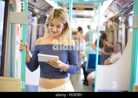 Giovane donna sul treno di lettura delle note Foto Stock