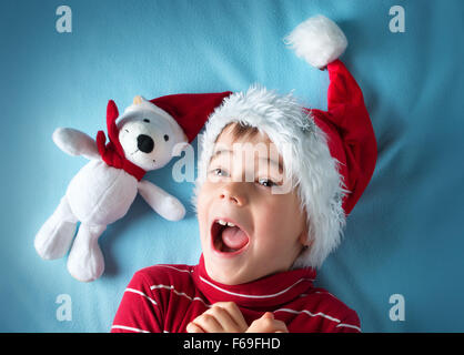 Felice ragazzo in santa claus hat con un orso bianco su sfondo blu Foto Stock