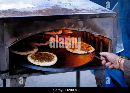 Una donna araba israeliana cuoce il tradizionale pane Pita spalmato con olio d'oliva e Zaatar nella città araba mista ebraica di Maalot-Tarshiha, nel Distretto del Nord in Israele Foto Stock