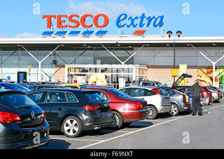 Supermercato Tesco Extra Parcheggio auto shopper carrello di caricamento del contenuto nel bagagliaio della vettura a East London store oscurato targhe England Regno Unito Foto Stock