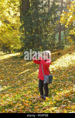 Ragazzo giovane Scattare foto nella foresta autunnale Foto Stock