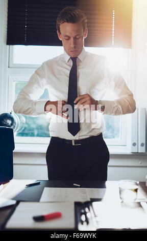 CEO executive business tipo maschio bianco la legatura la cravatta mentre permanente al desk presso il suo ufficio, concetto di successo Foto Stock