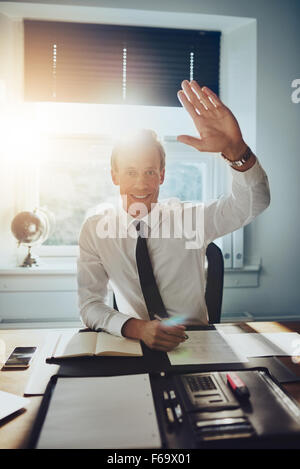 Business man dando alta cinque alla telecamera mentre sorridente, indossa una tuta e tirante Foto Stock