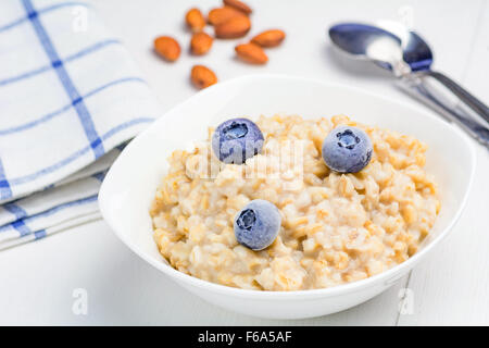 Farina di avena porridge nel recipiente con mirtilli e mandorle, close up Foto Stock