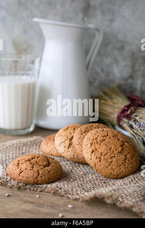 Chocolate Chip Cookie di fiocchi d'avena, lavanda essiccata e latte sul panno di lino. Campagna ancora vita Foto Stock