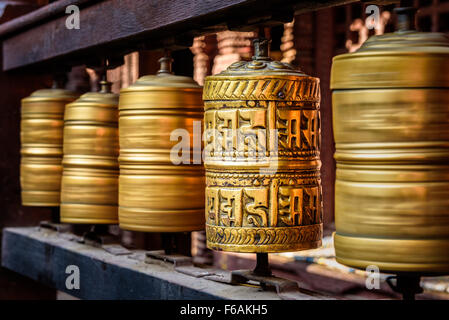 Golden il tibetano ruote della preghiera in un tempio buddista in Nepal Foto Stock