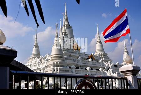 Samut Prakan, Thailandia: luccicanti Wat Asoke con il suo anello di sette spired Chedis e il rosso, bianco e blu bandiera tailandese Foto Stock