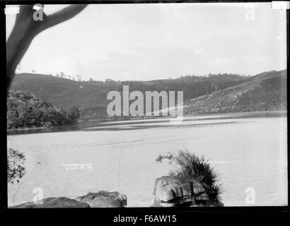Questa fotografia del 1910 di Gilmour Brothers cattura la bellezza serena della baia di Waitangirua a Raglan, nuova Zelanda. L'immagine mette in risalto l'ambiente naturale e il paesaggio costiero panoramico dell'area durante i primi anni del XX secolo. Foto Stock
