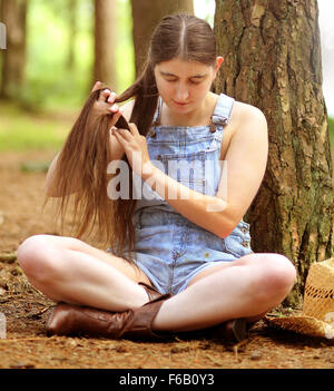 Paese tra i boschi ragazza nel vecchio dungaree tagliati corti nei boschi, Luglio 2014 Foto Stock